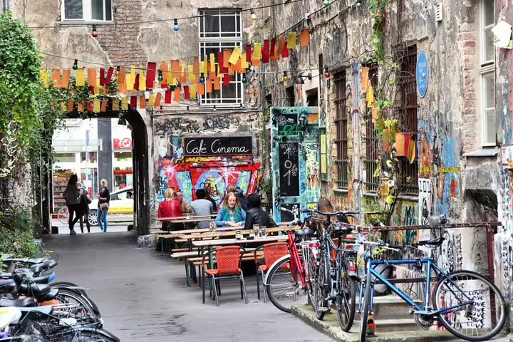 Cafe Cinema courtyard in Berlin with colorful bunting, graffiti walls, outdoor seating, and bicycles