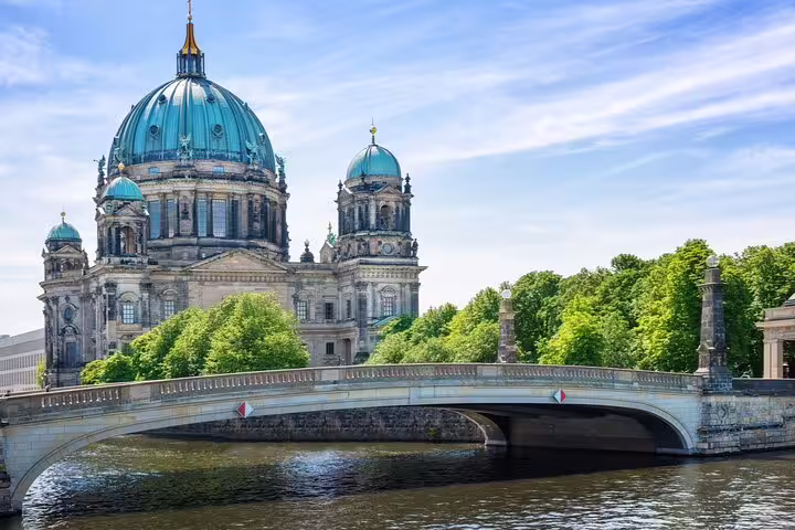 Berlin Cathedral with green copper dome reflected over Spree River and historic stone bridge