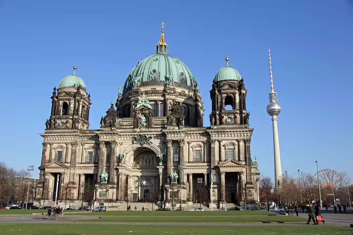 Berlin Cathedral with green copper domes and TV Tower against clear blue sky