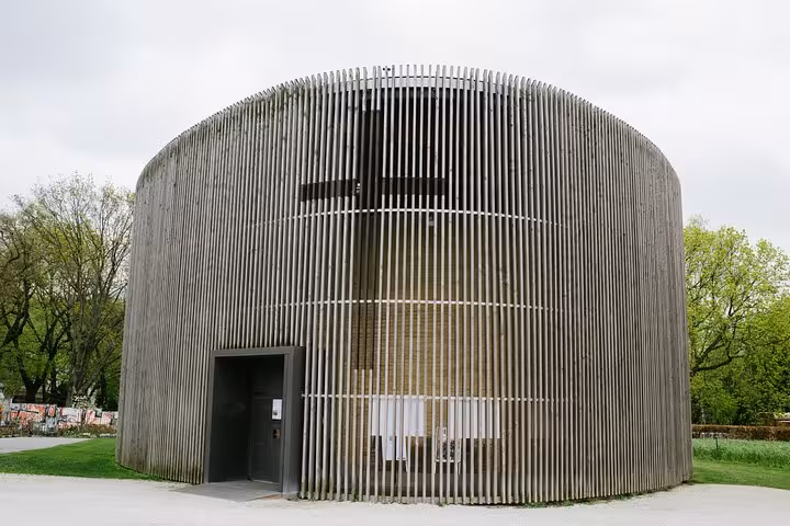 Circular modern chapel with wooden slat facade and cross in Berlin park