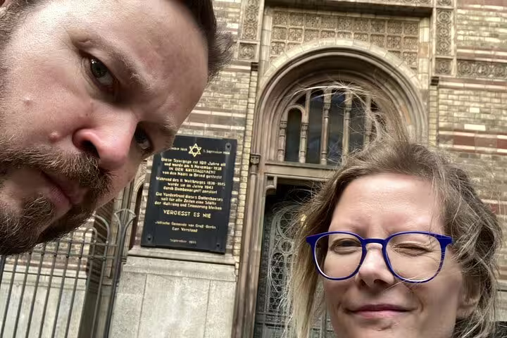 Couple taking selfie in front of Berlin synagogue memorial plaque during self-guided walking tour