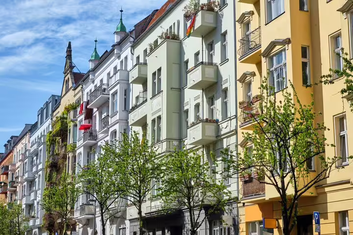Colorful historic apartment buildings with balconies lining a tree-lined street in Berlin