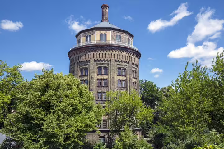 Historic Berlin water tower surrounded by lush green trees under a blue sky