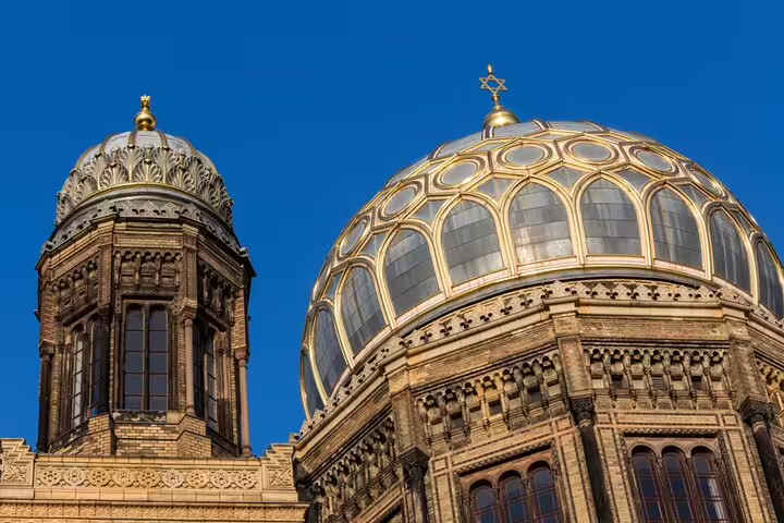 Golden dome and ornate tower of the New Synagogue in Berlin under blue sky