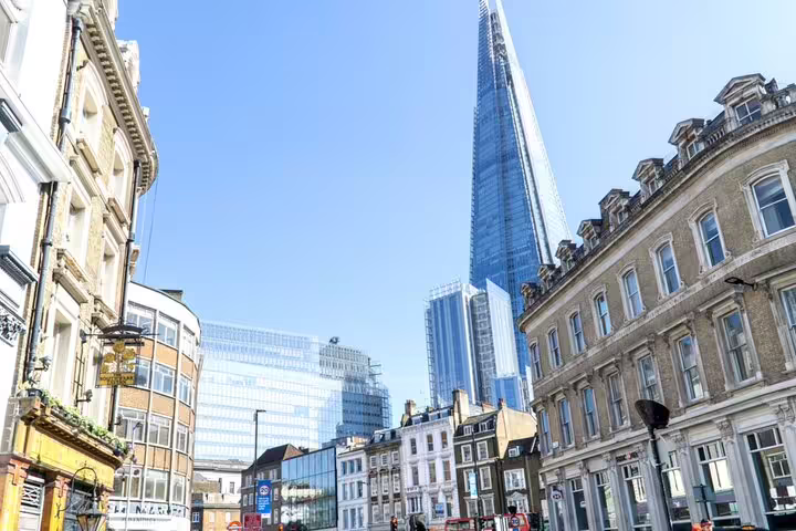 The Shard skyscraper towering over historic Bermondsey street buildings under clear blue sky, London