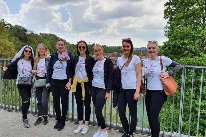 Group of friends on a bridge viewpoint in Bern, Switzerland, enjoying a self-guided scavenger hunt and sights tour