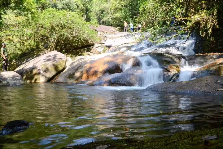 Serene waterfall cascading over rocks in lush Bertioga forest, perfect for a coastal trail adventure.