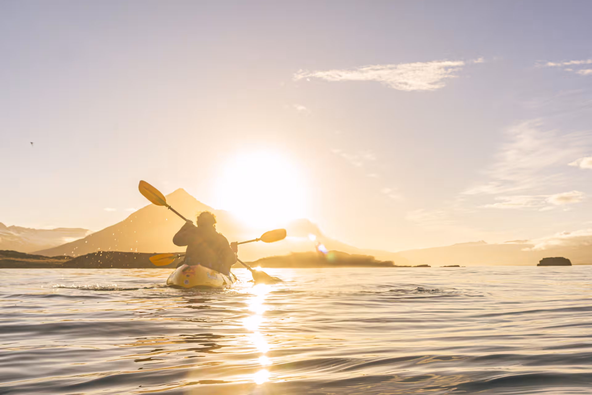 Solo kayaker explores Berufjörður under a vibrant sunrise, capturing the serene beauty of Iceland's East Fjords.