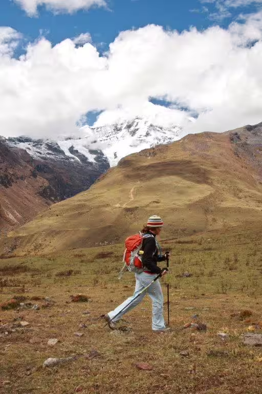 Hiker with trekking poles in Bhutan's scenic mountain landscape during a 12-day adventure tour.