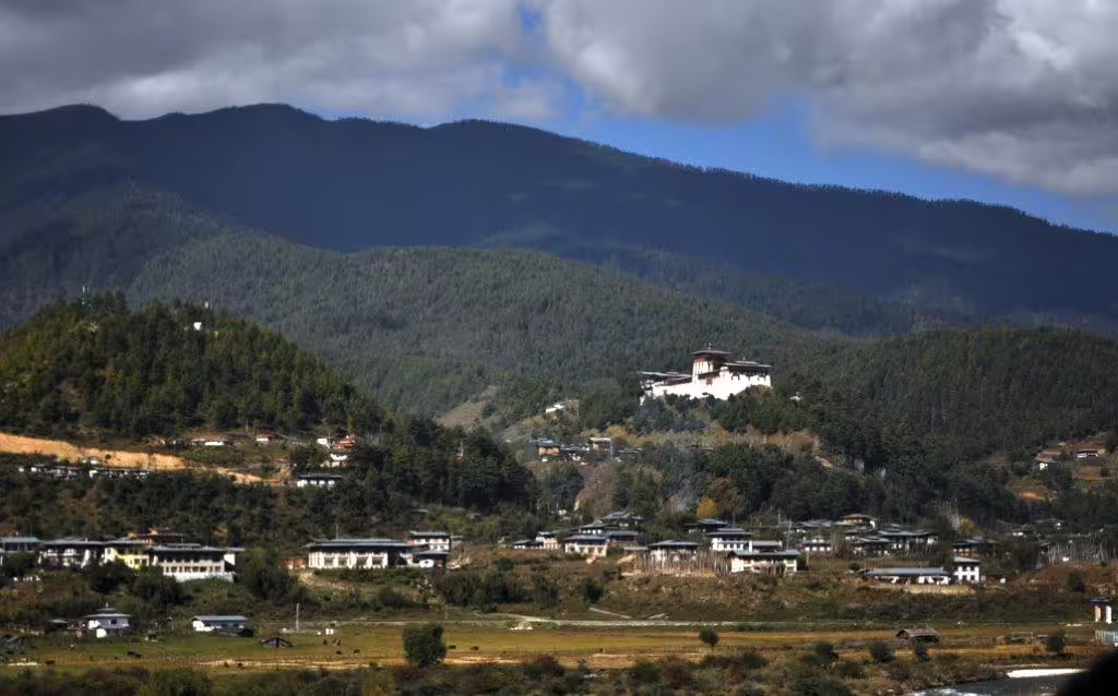 Scenic view of Bhutanese village nestled in lush mountains, highlighting cultural landscapes on an 8-day Bhutan tour.