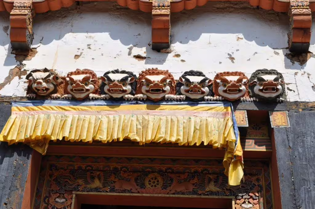 Intricately carved Bhutanese temple facade with vibrant colors, showcasing traditional artistry on a 12-day tour.