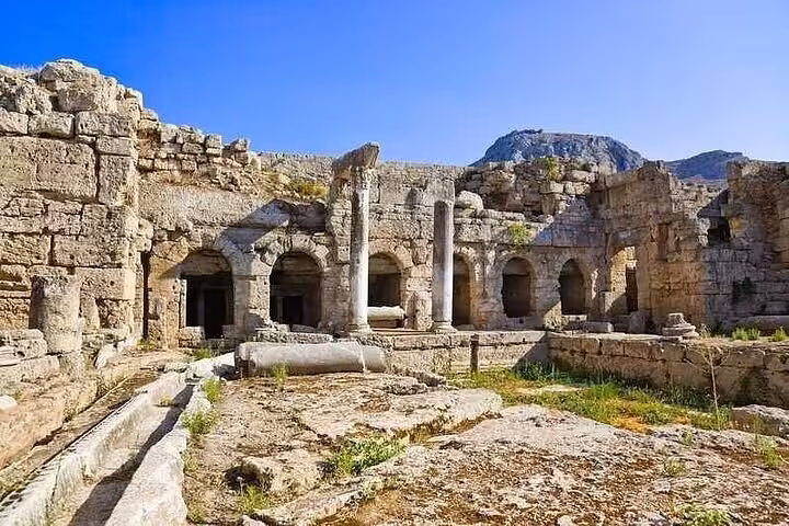 Ancient Corinth ruins with arched stone chambers and columns, a highlight of the Biblical Corinth wine and oil tasting tour