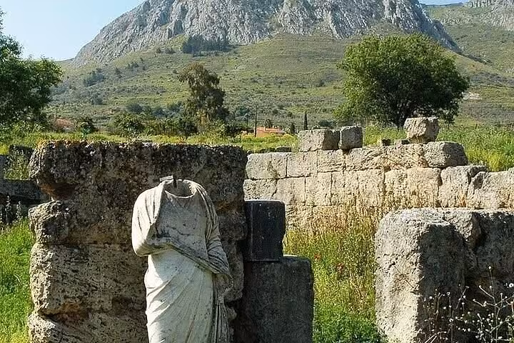 Headless ancient statue among Corinth archaeological ruins with mountain views on Biblical Corinth faith tour and tasting