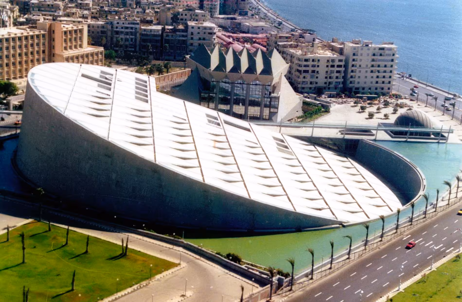 Aerial view of the Bibliotheca Alexandrina library with its iconic tilted circular roof beside the Mediterranean Sea