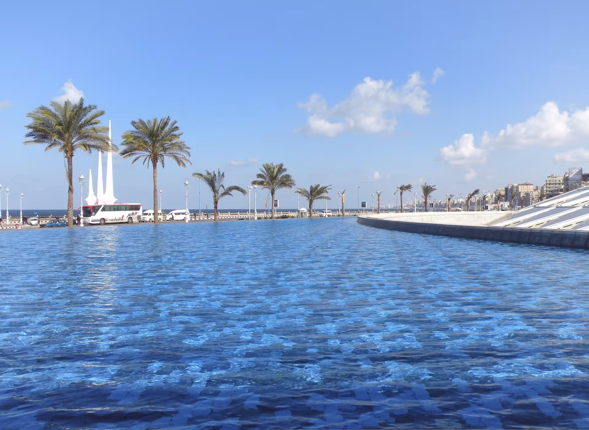 Reflecting pool at Bibliotheca Alexandrina with palm trees and Mediterranean coastline in Alexandria, Egypt