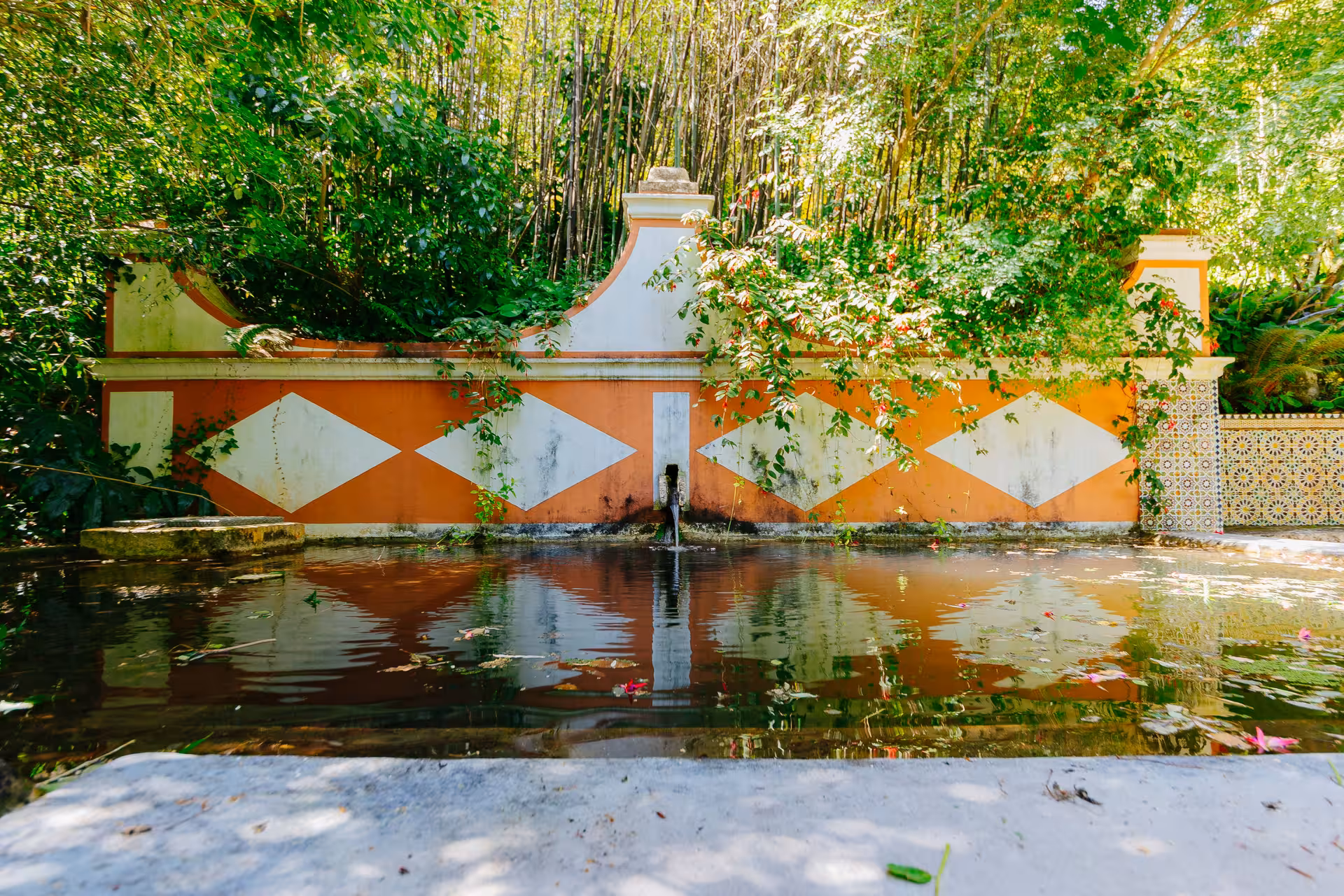 Ornate fountain and reflective pool at Biester Palace gardens in Sintra with vibrant tiled walls