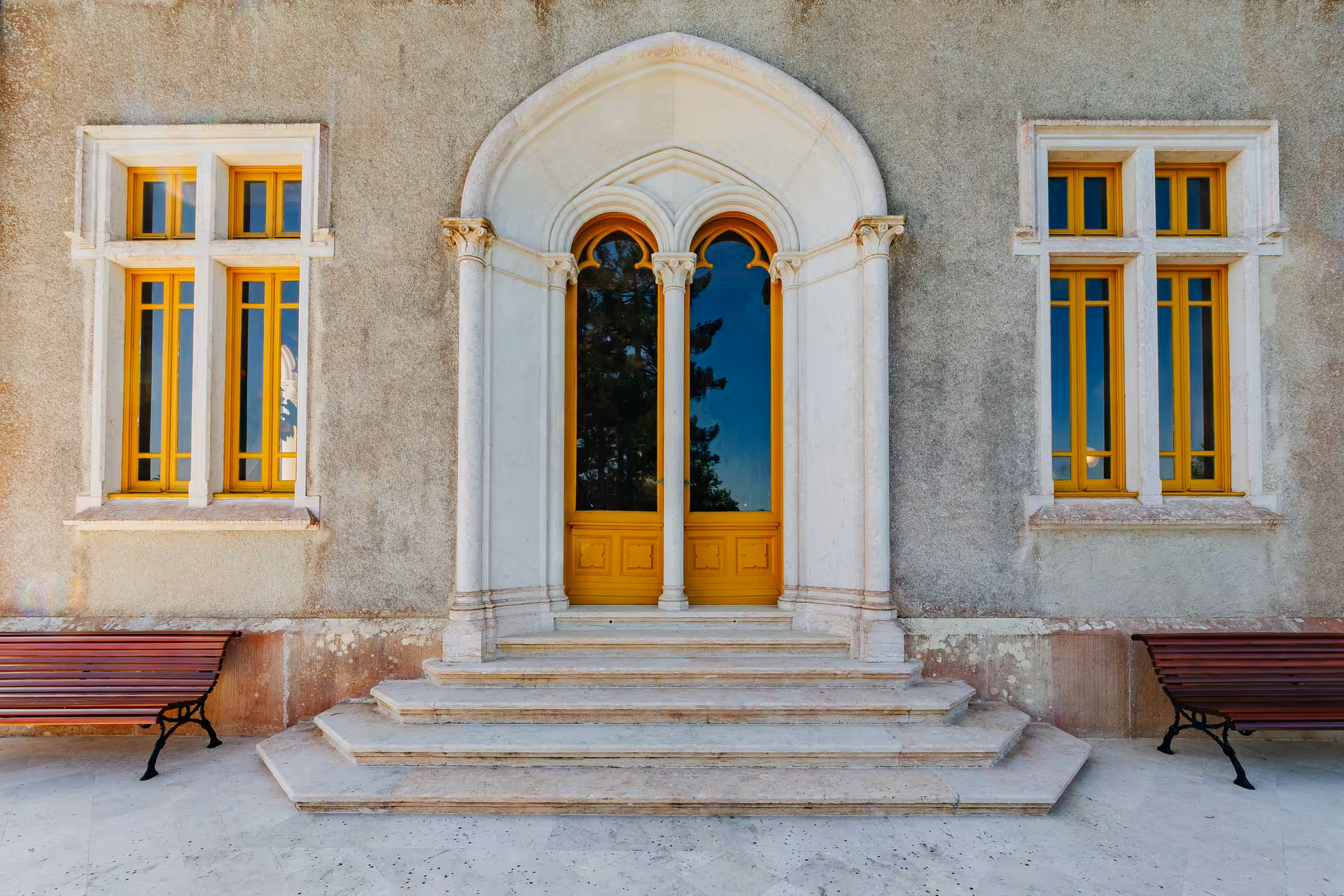 Elegant Gothic arched entrance of Biester Palace in Sintra with golden yellow doors and marble steps