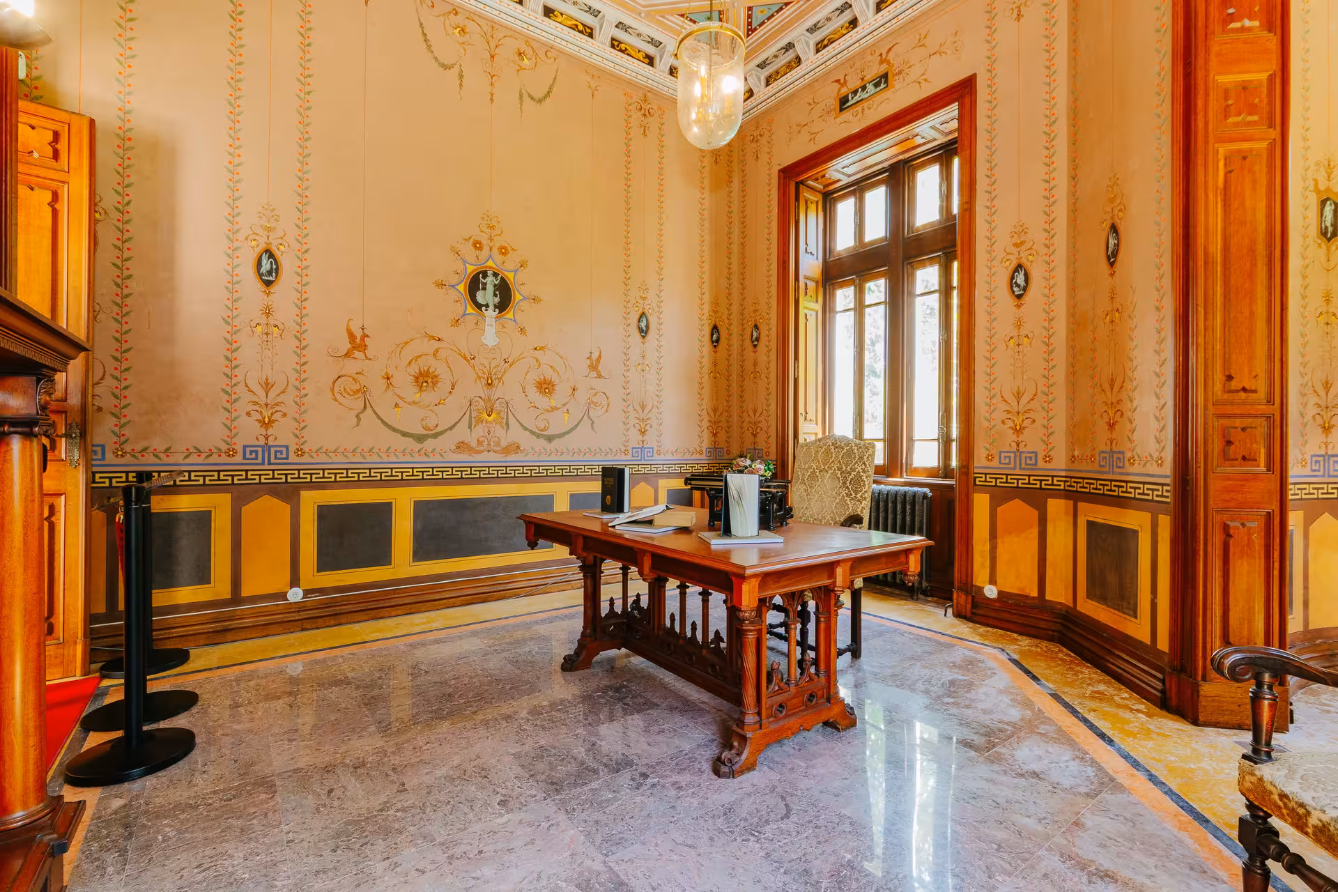 Ornate interior room of Biester Palace Sintra featuring hand-painted walls and antique wooden desk