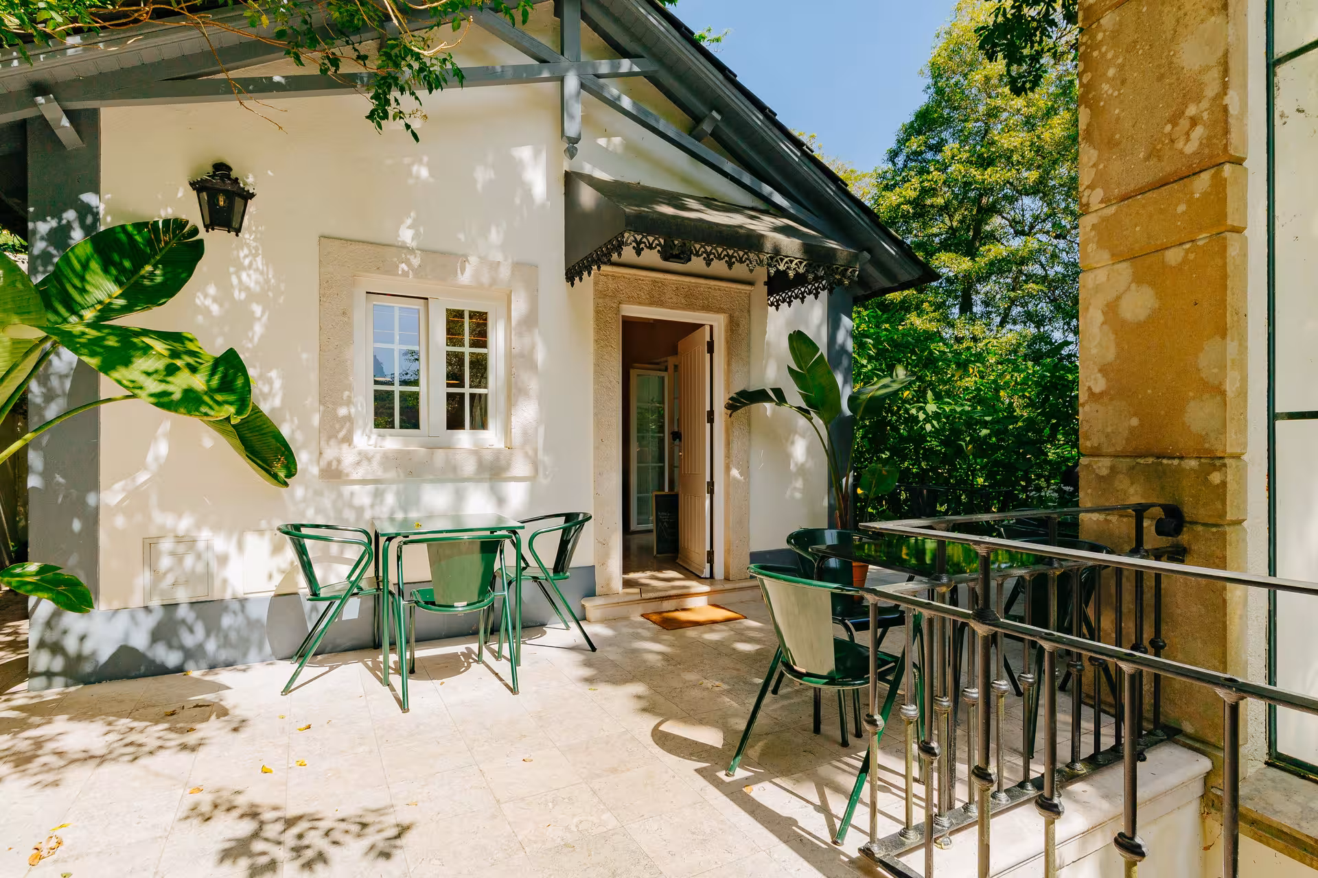Sunny terrace at Biester Palace Sintra with green garden furniture and tropical plants