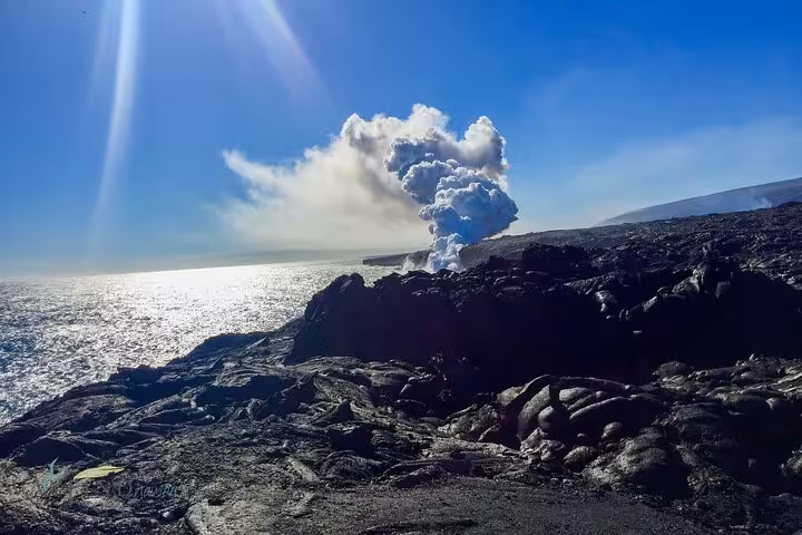 Volcanic steam rises from rugged lava fields against a bright blue sky on Hawaii's Big Island tour.