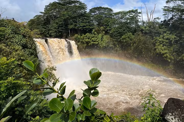 Scenic waterfall on Hawaii's Big Island with a vibrant rainbow and lush greenery on the Volcano, Waterfalls & Coffee Tour.
