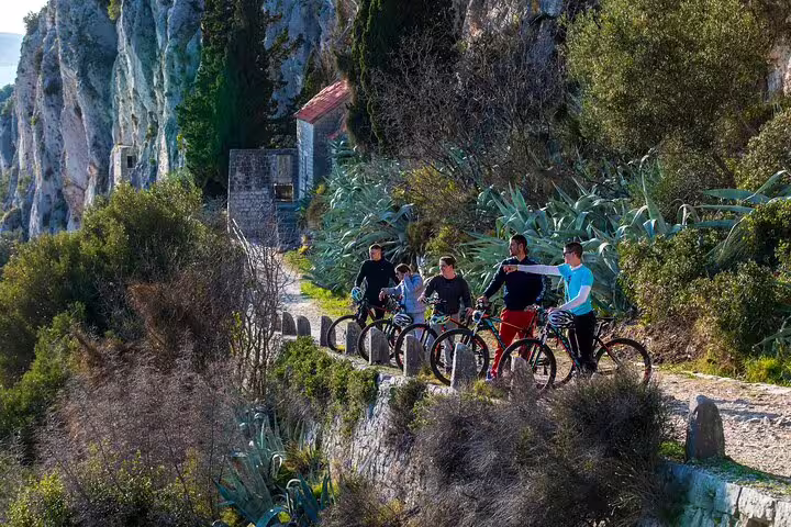 Friends biking along a scenic cliffside path near Split on the Bike, Beer & Poljud Stadium Tour