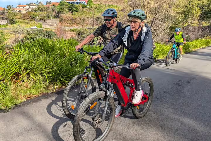 Cyclists enjoy a scenic bike tour on Madeira's west coast, navigating lush landscapes and sunny trails.
