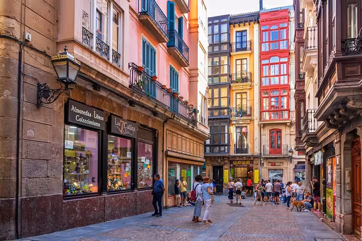 Colorful street view in Bilbao's old town with vibrant buildings and people exploring, ideal for Santander day tours.
