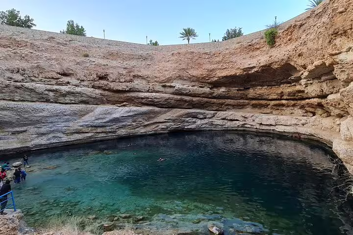 Visitors enjoying the crystal-clear waters of Bimmah Sinkhole, a captivating geological feature near Muscat, Oman.