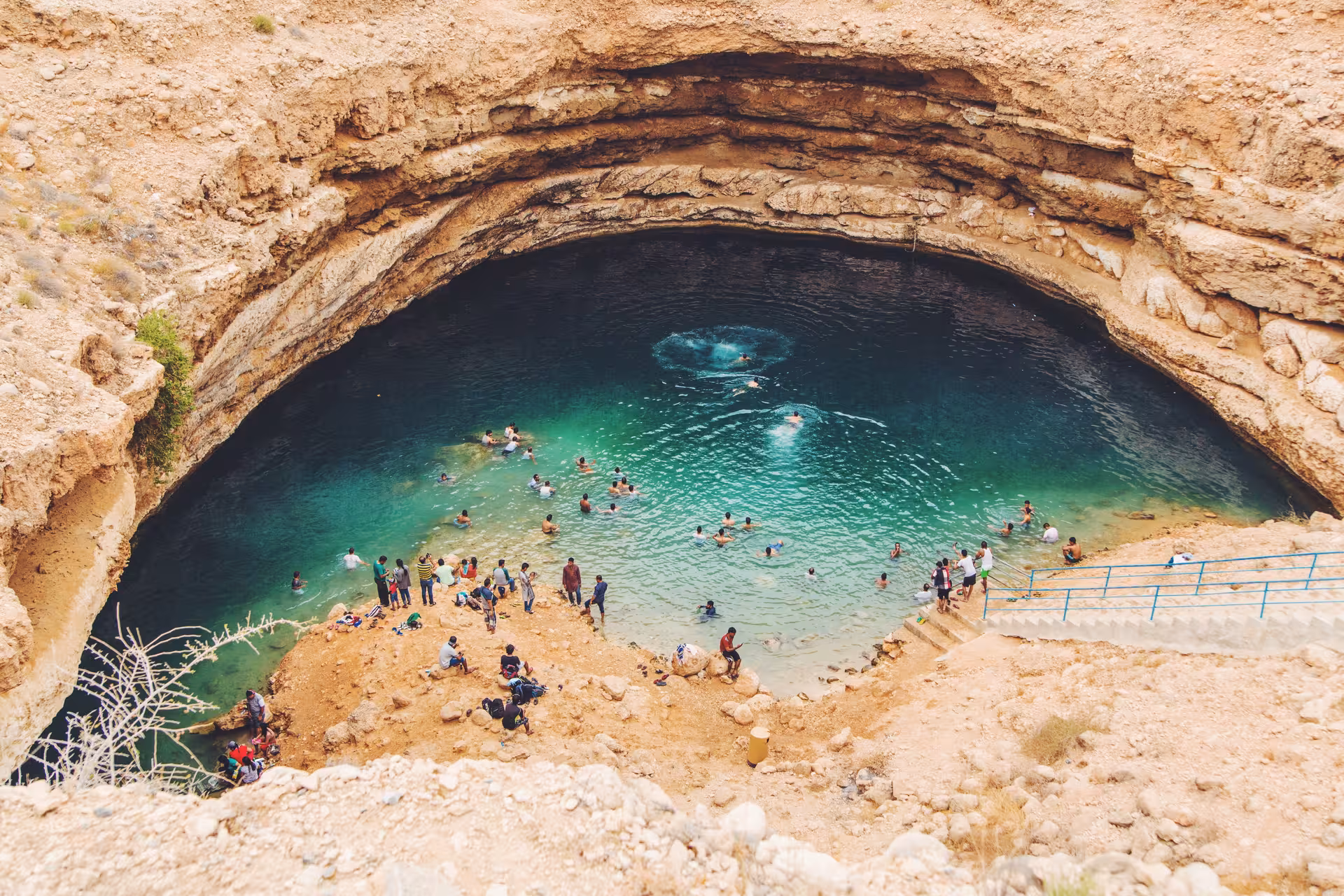 Visitors swimming in turquoise water at Bimmah Sinkhole, a must-see stop on the Wadi Shab full day tour in Oman