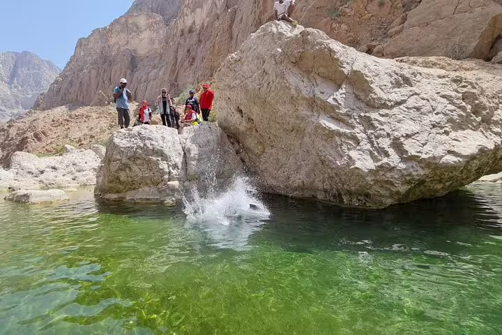 Tourists enjoy a refreshing swim and rock jumping at the scenic Wadi Al Arbeieen during a full-day Oman tour.