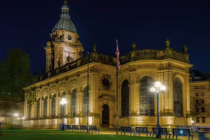 Birmingham Cathedral illuminated at night with street lamps and benches in foreground