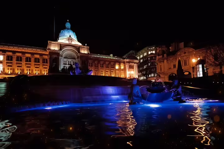 Birmingham Council House illuminated at night with blue-lit fountain in Victoria Square