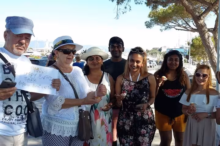 Group of tourists celebrating a birthday on a boat tour near Saint-Tropez, holding a Happy Birthday sign