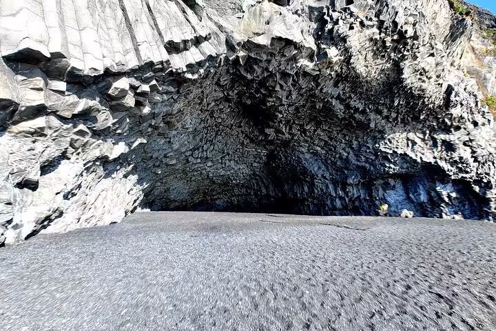 Black basalt cave with hexagonal rock columns on Iceland's volcanic south coast beach