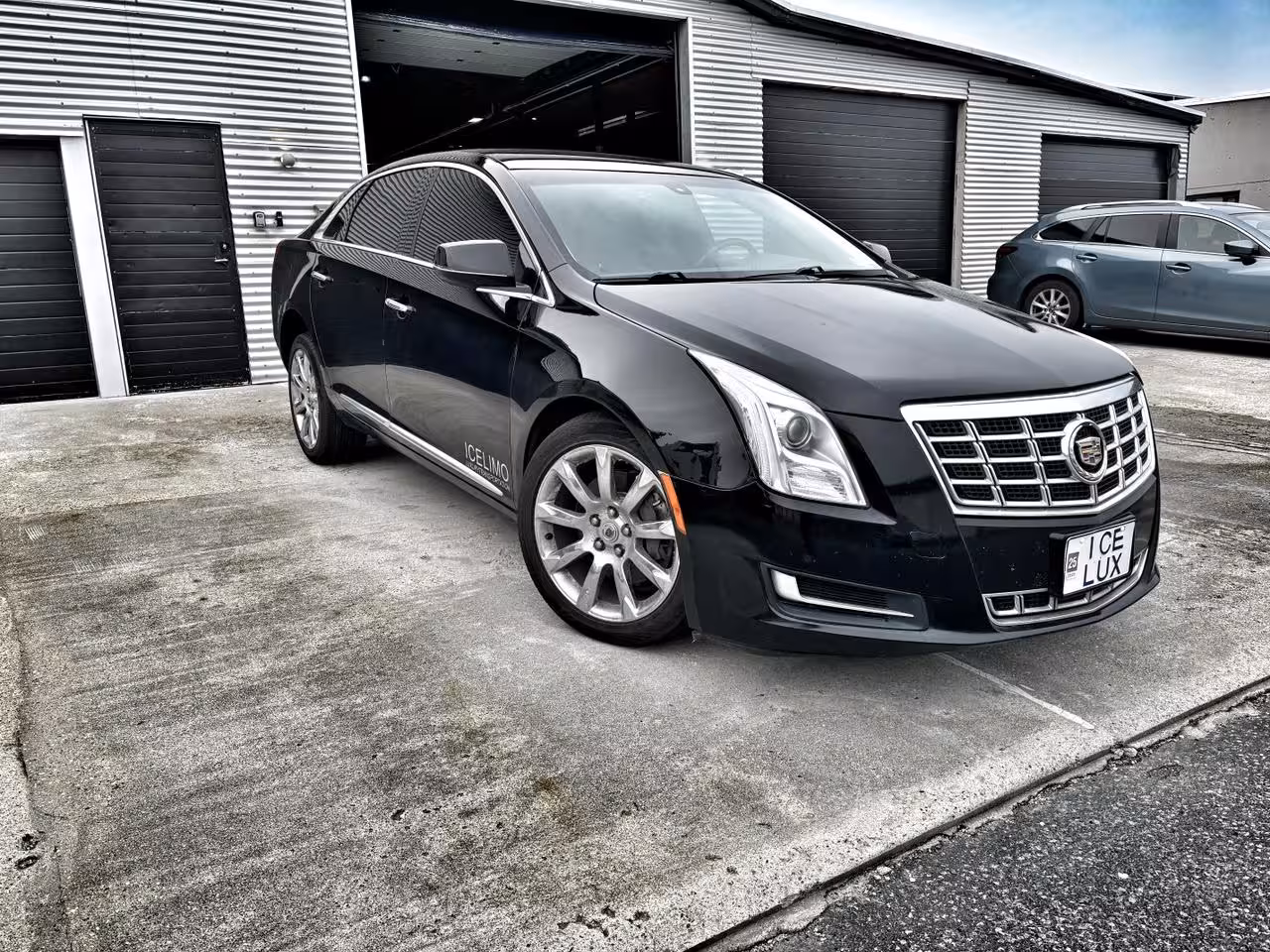 Black Cadillac XTS sedan parked outside garage, used for private transfers between Reykjavik and Keflavik Airport