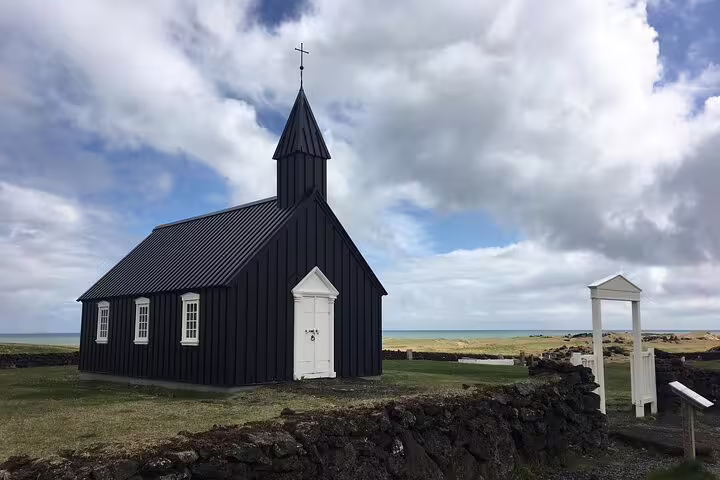 Black wooden church with white door and cross steeple on Snaefellsnes Peninsula, Iceland