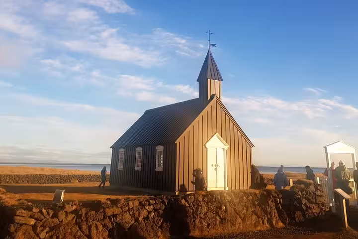 Black church of Budir on Snaefellsnes Peninsula Iceland with ocean backdrop at golden hour