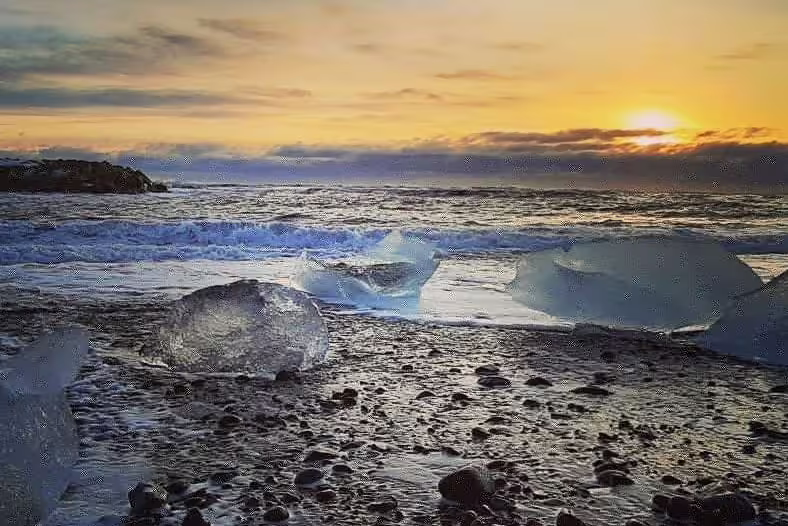 Ice chunks on black sand beach at golden sunset near Jokulsarlon Glacier Lagoon, Iceland