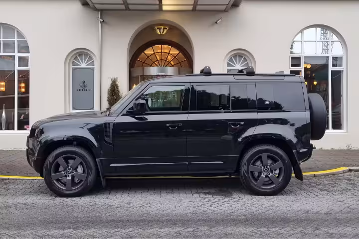 Black Land Rover Defender luxury SUV parked outside elegant building in Reykjavik