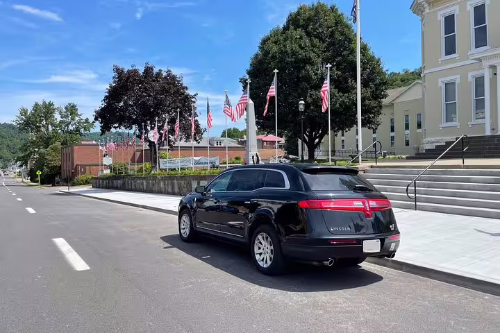 Black Lincoln MKT SUV parked near a town hall with American flags on a sunny day