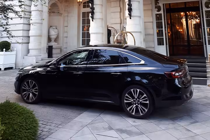 Black luxury sedan parked at elegant Parisian hotel entrance for private airport transfer