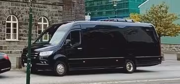 Black luxury Mercedes Sprinter van parked on city street near stone building