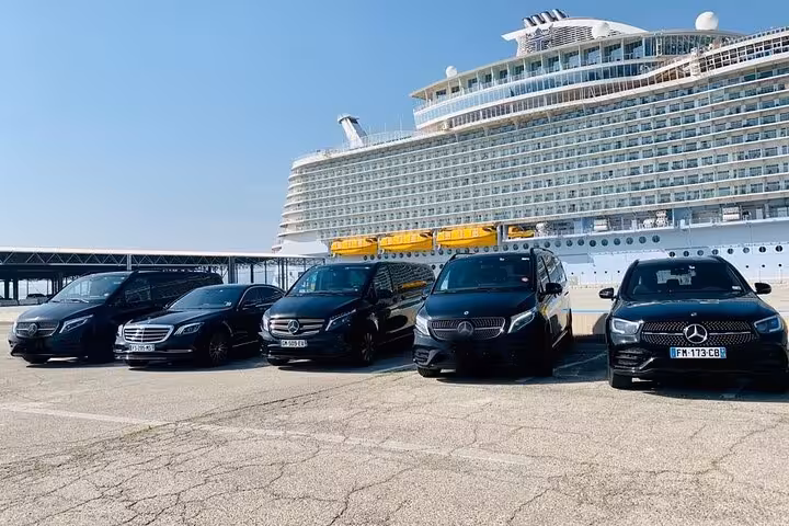 Fleet of black Mercedes vehicles parked at Marseille cruise port with large cruise ship in background