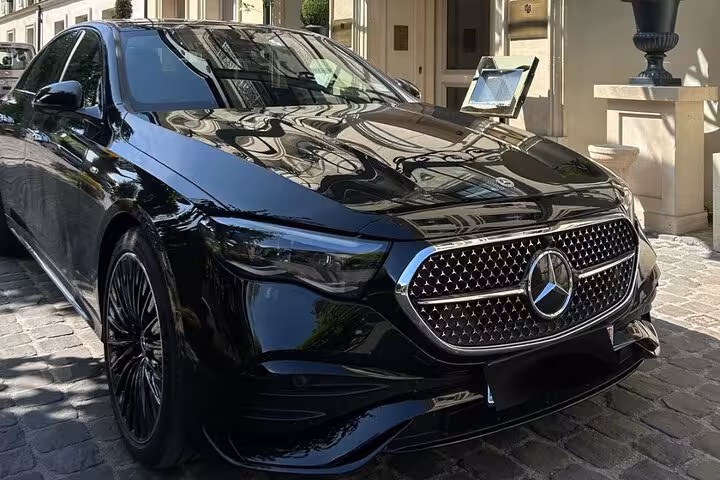 Black Mercedes-Benz luxury sedan parked on cobblestone street outside elegant building