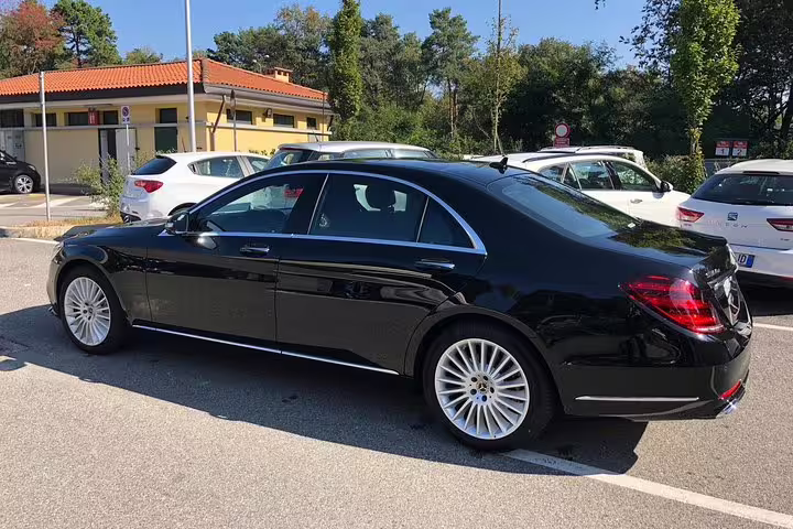 Black Mercedes-Benz luxury sedan parked in sunny lot for private airport transfer service
