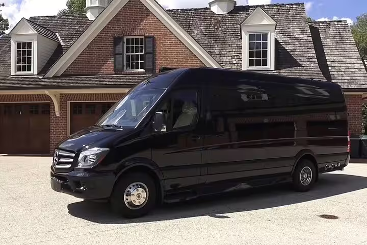 Black Mercedes Sprinter luxury van parked in front of brick house for private transfer service