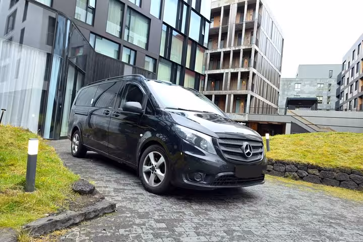 Black Mercedes-Benz Vito minivan parked outside modern Reykjavik building for Golden Circle private tour