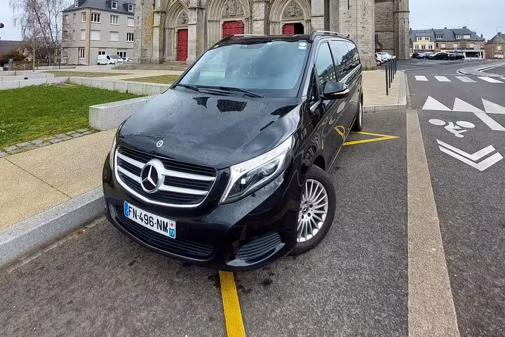 Black Mercedes-Benz V-Class minivan parked in front of a French church, license plate FN-496-NM