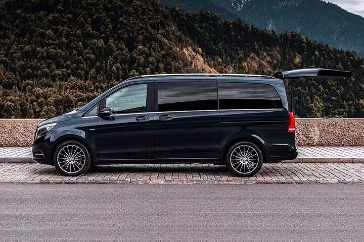 Black Mercedes-Benz V-Class luxury minivan parked with mountain forest backdrop